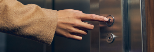 Hand pressing elevator button to go up